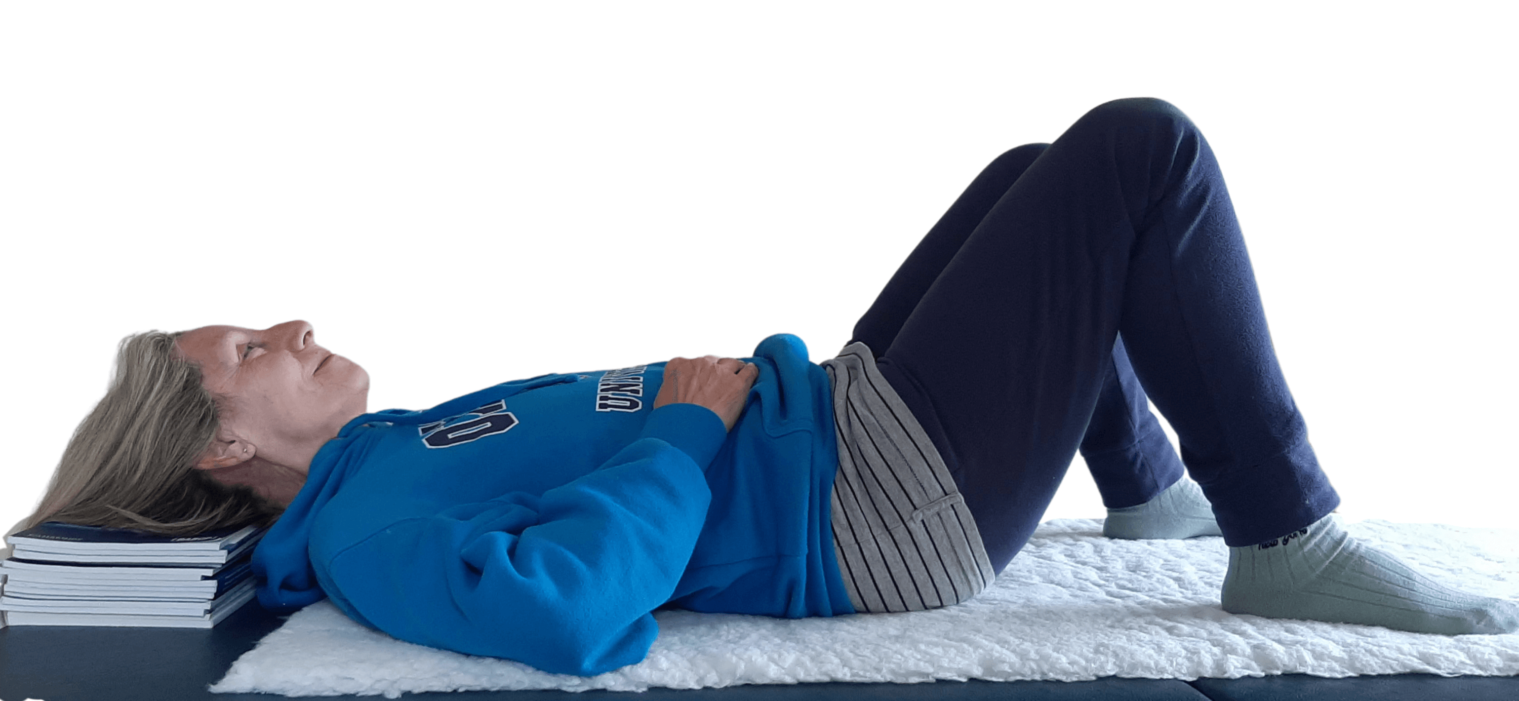  Person lying on back, knees bent, hands on tummy, head resting on books