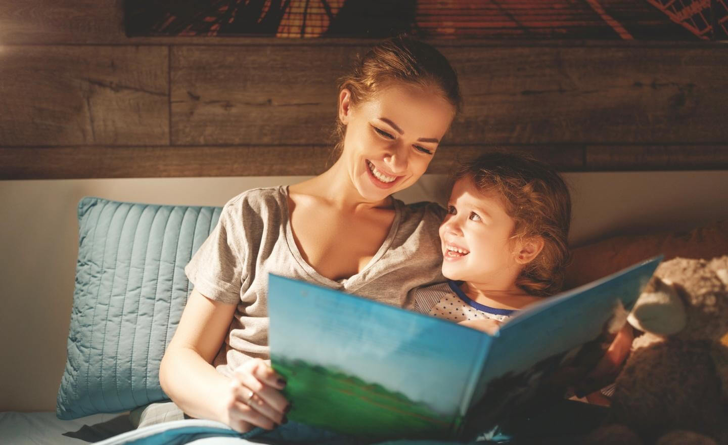  Mom reading a bedtime story to her child in bed after resolving sleep struggles with expert support