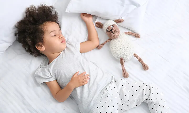  Young child sleeping independently with a comfort item after learning healthy sleep habits