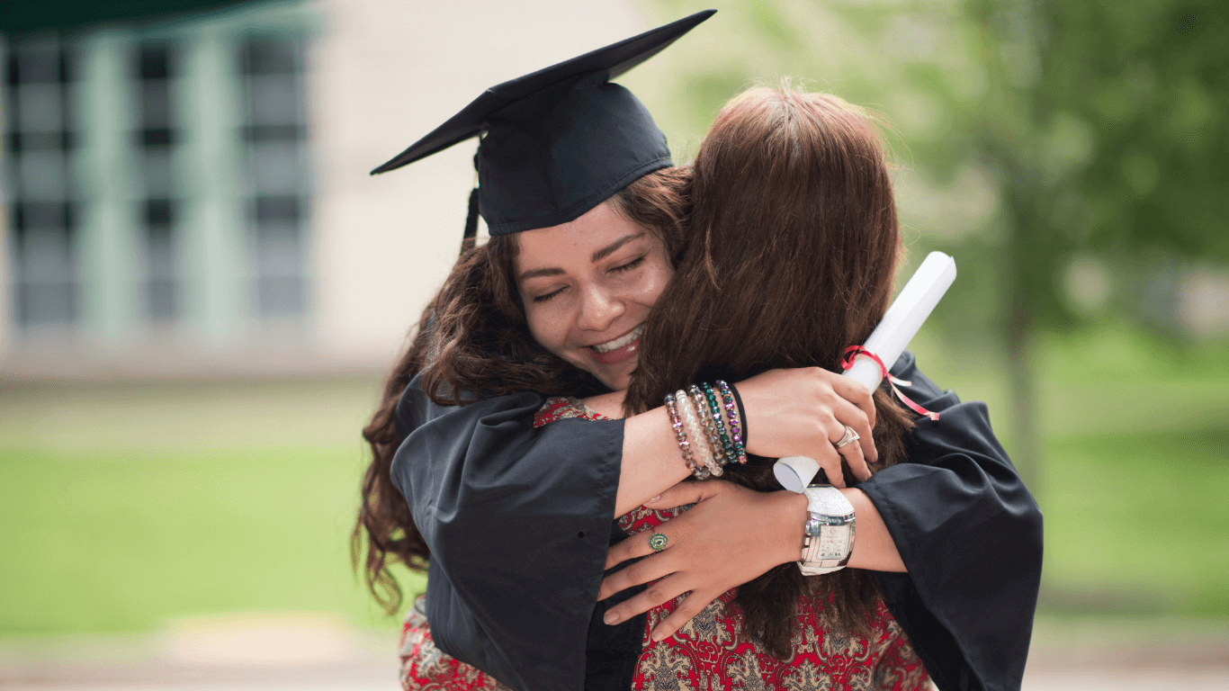 Female college graduate hugging her mother at graduation