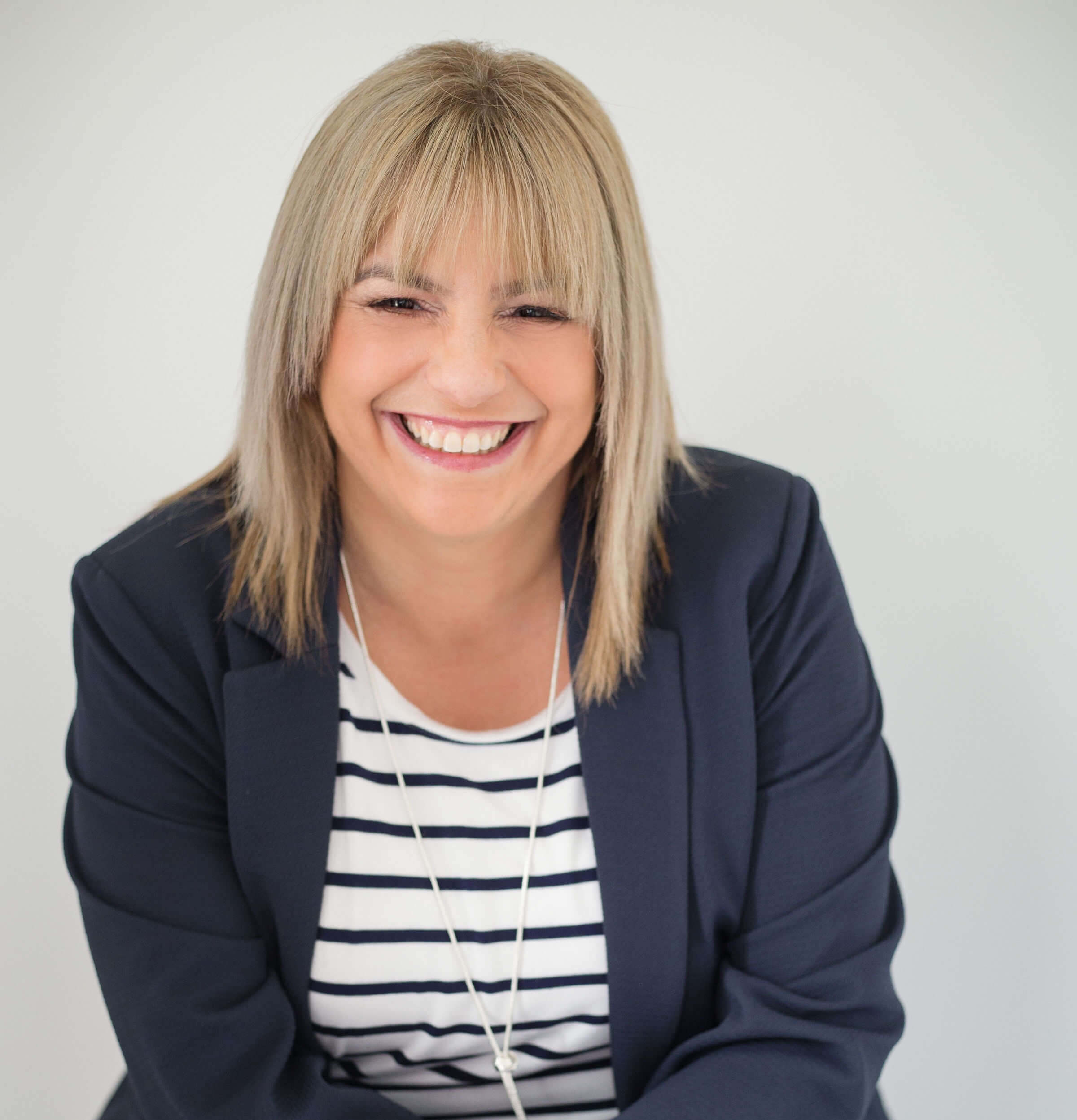 Hana Zawodny sitting on a chair, facing the camera, promoting hypnotherapy and brain training for stress reduction and weight loss.