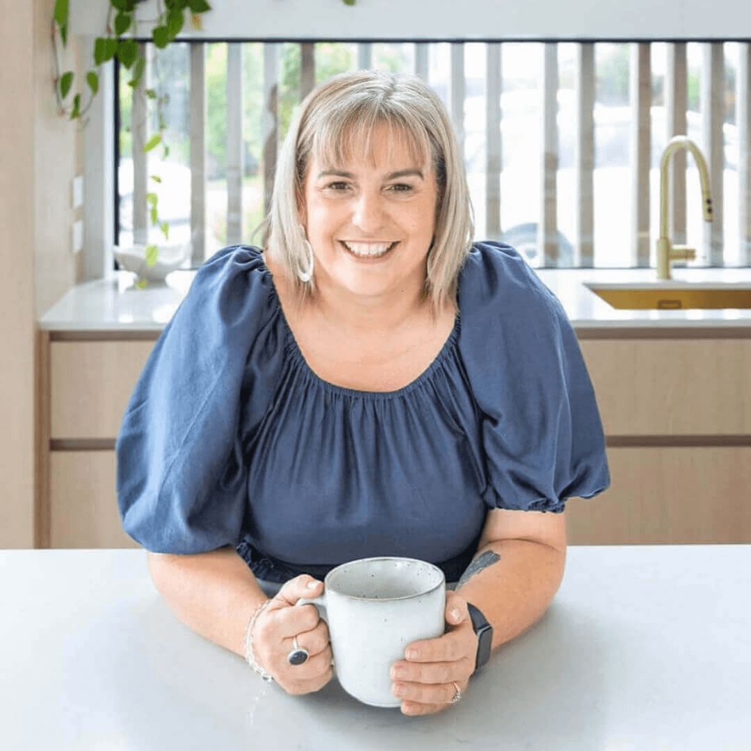  Hana Zawodny, Brisbane-based hypnotherapist and women’s wellness coach, smiling warmly in a kitchen setting, specialising in burnout recovery and menopause support.